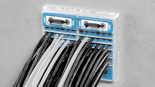 Kabelgenomföring från Roxtec med flera kablar monterade i ett väggfäste, känt för sin brand- och framtidssäkerhet.