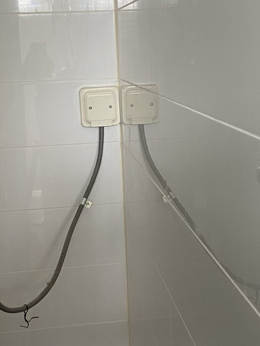 Dubbla eldosor på vitt kakel i ett hörn, kablar synliga längs väggen. Fråga om hur man tätar omkring eldosorna inför montering av duschväggar.