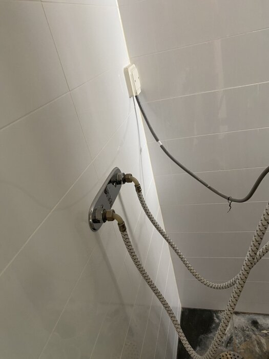 Anslutningar och elkontakt på badrumsvägg där duschväggar ska installeras.