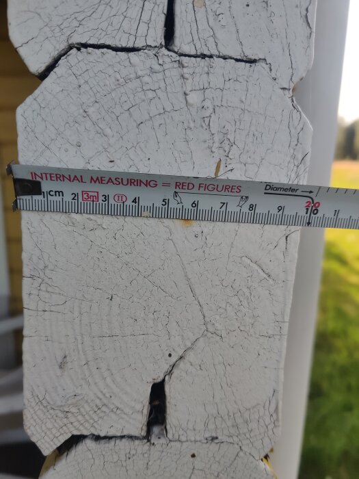 Träbit med vit färg och sprickor, bredvid ett måttband. Söker liknande profil för 60-talets byggsatser och prefabricerade bodar och fritidshus.