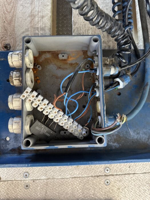 Elektrisk kopplingsbox med flera kablar och kontakter, utan manöverdon. Finns i ett garage för installation av ett lyftbord.