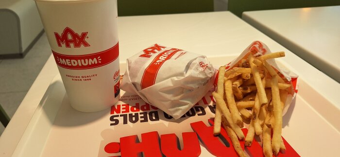 Burgarmeny med pommes frites och en mediumdryck från Max på bricka.