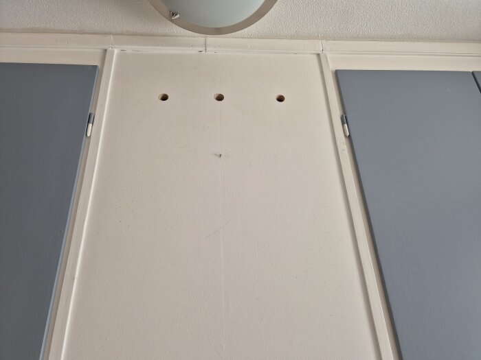 Vägg med tre hål ovanför skåp, där ventilationsfläkten har kopplats bort i bostadsrättslägenhet.