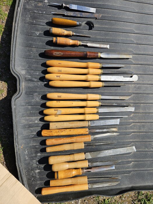 Olika svarvstål med trähandtag, placerade på en matta, några märkta med "Luna". Totalt ca 16 stycken verktyg i varierande storlekar.