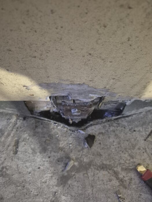 Glipa mellan betongplatta och vägg i garage med ojämn yta, markerad av spår och materialrester.