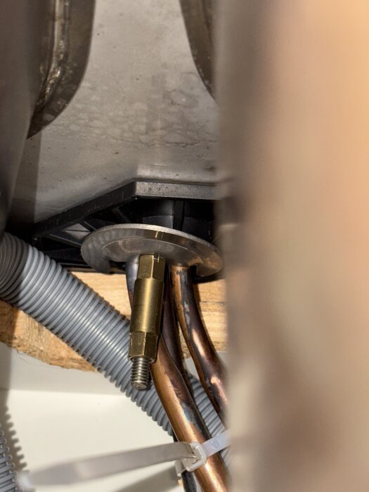 Vy under diskbänk med rör och kopplingar, visar en anslutning utan synliga avstängningsventiler, relaterad till köksrenovering.