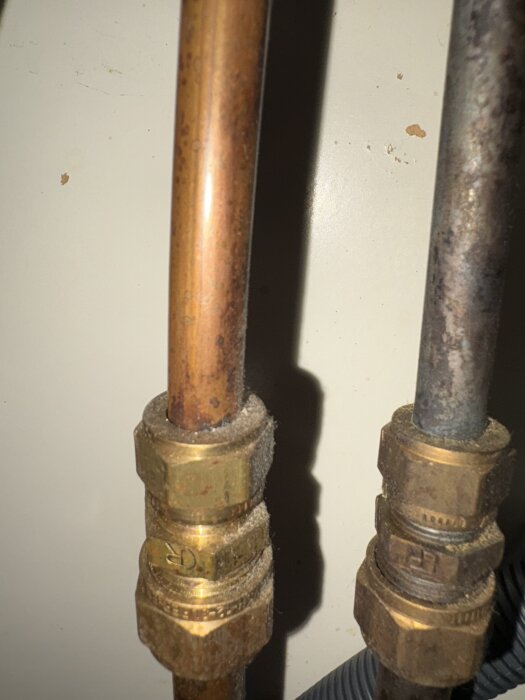 Två kopparrör med mässingskopplingar under diskbänken, ett av dem kopplat till utomhusslang, saknar avstängningsventiler.