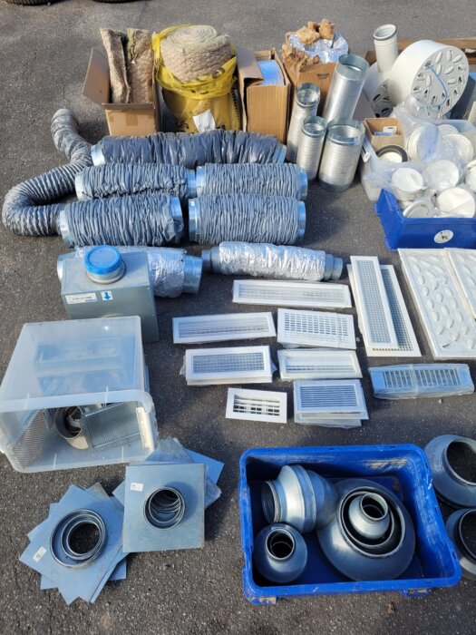 Ventilationsdelar och tillbehör inklusive spirorör, ventiler och isoleringsmaterial upplagda på marken, redo för försäljning.