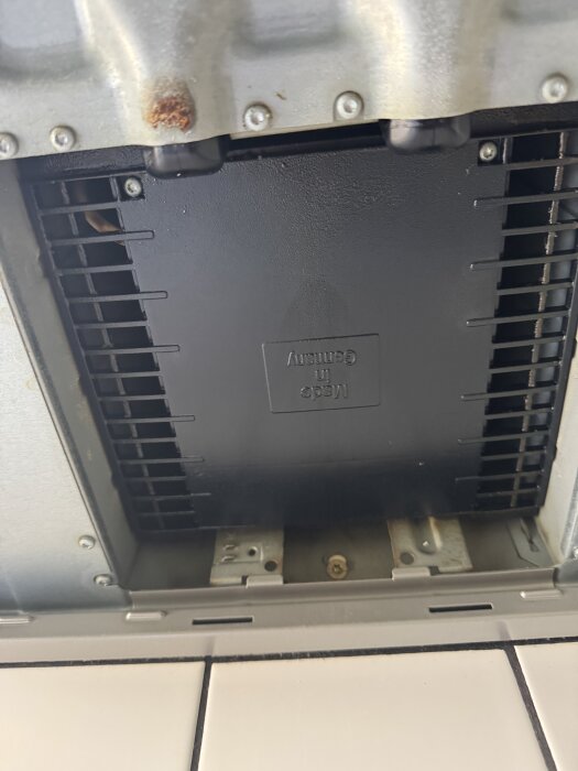 Undersida av en köksfläkt med synliga skruvar och öppningar; kolfilter saknas.