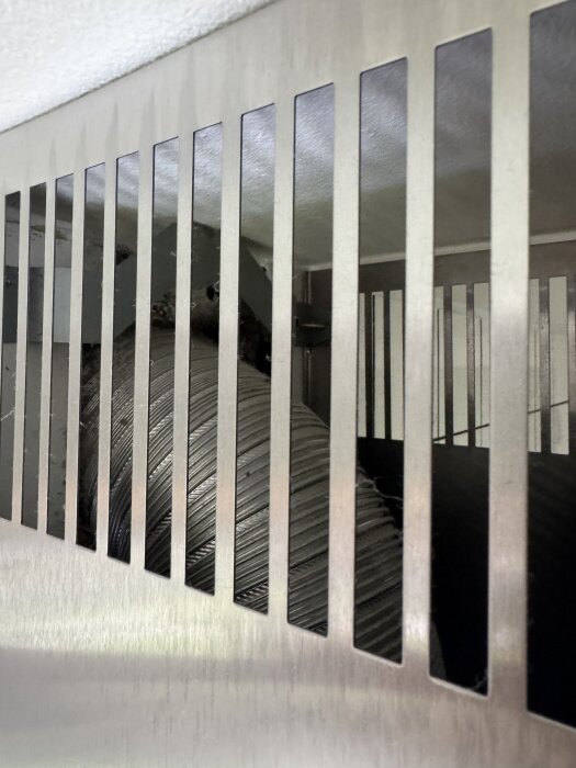 Närbild av en metallkåpa med spalter till en köksfläkt där ett nytt kolfilter ska installeras enligt OVK-krav.