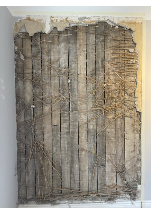 Reveterad vägg med synliga träreglar och lerkärningsrester i en lägenhet från 1914; del av diskussion om bärande väggar.