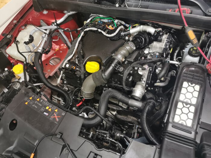 Motorutrymme på en Renault Megane 2020 under service och kamremsbyte, med synliga kablar och komponenter.
