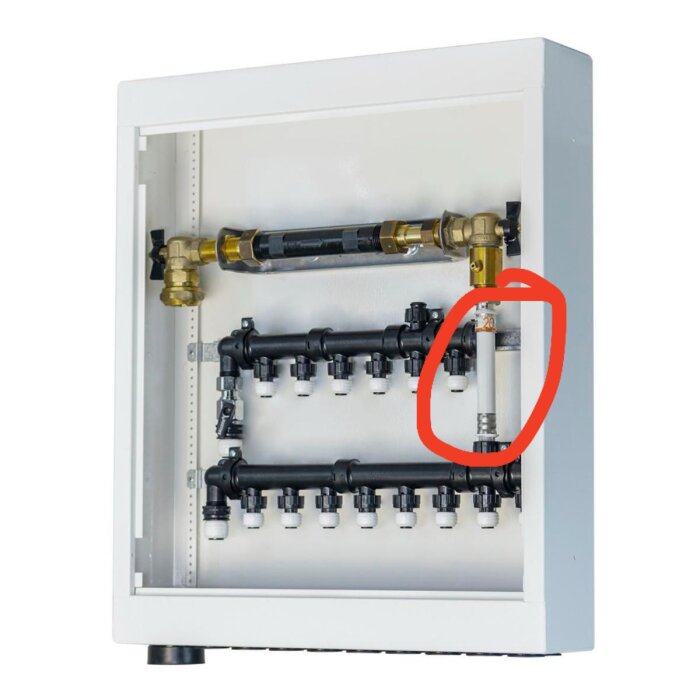 Vattenmätarskåp med rör och anslutningar, en del inringad i rött visar potentiell plats för vattenfelsbrytare.