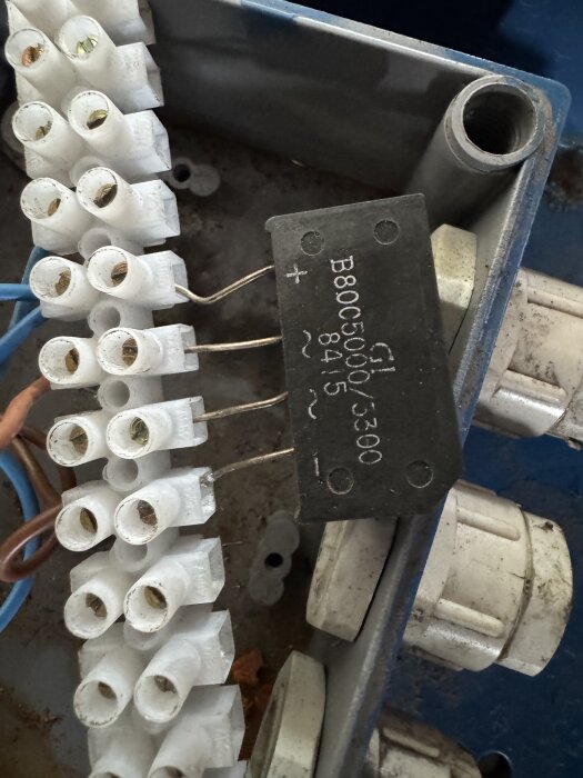 Elektriska anslutningar med en svart komponent märkt B80C5000/3300 tillsammans med vita kopplingsklämmor och kablar.