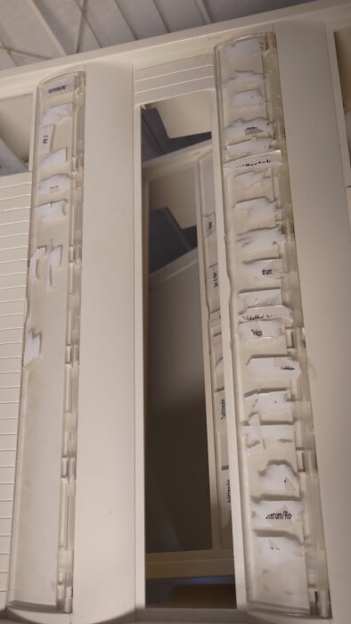 Gammal Hager Gamma central med trasiga dymo etiketter fastnade på genomskinligt plastfönster, synlig text och försök att ta bort dem.