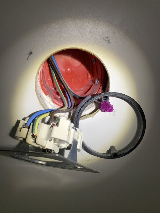 Elektrisk dosa med ledningar monterad bakom köksinredning, anslutna till ett Perilex-uttag. Fokuserar på installation och korrekt märkning.