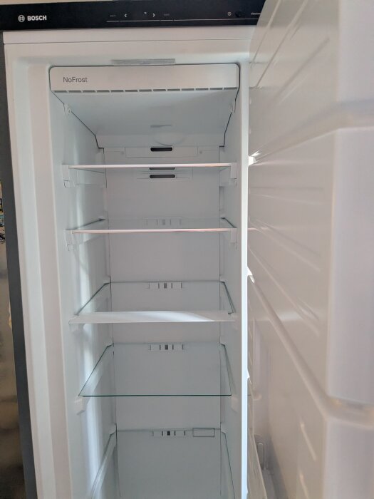 Öppen Bosch frys utan isbildning, med tomma hyllor och NoFrost-teknik.