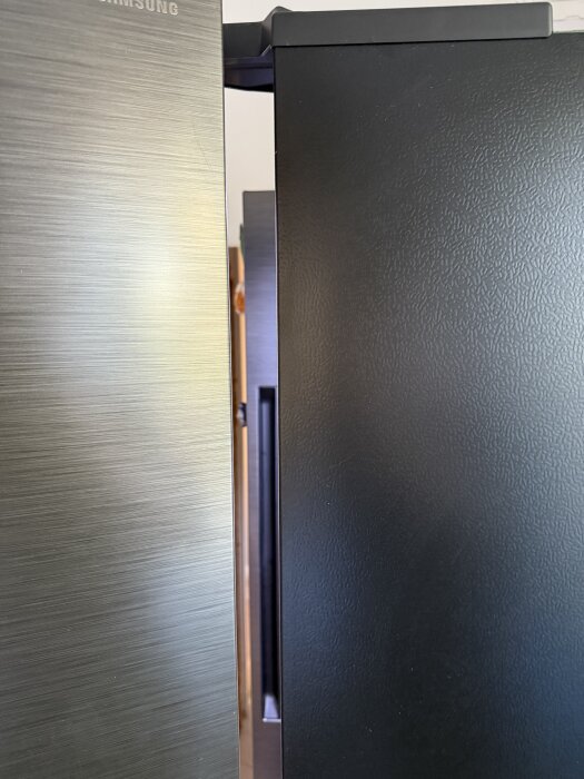 Side by side kylskåp delvis inbyggda i en vägg, med synliga dörrar. Bakdel i en hall, planering för vägg och golvnivåjustering.