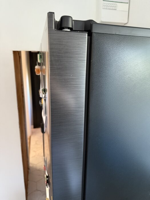 Side by side-kylskåp delvis inbyggt i en vägg med en öppning runtom, sedd från sidan.