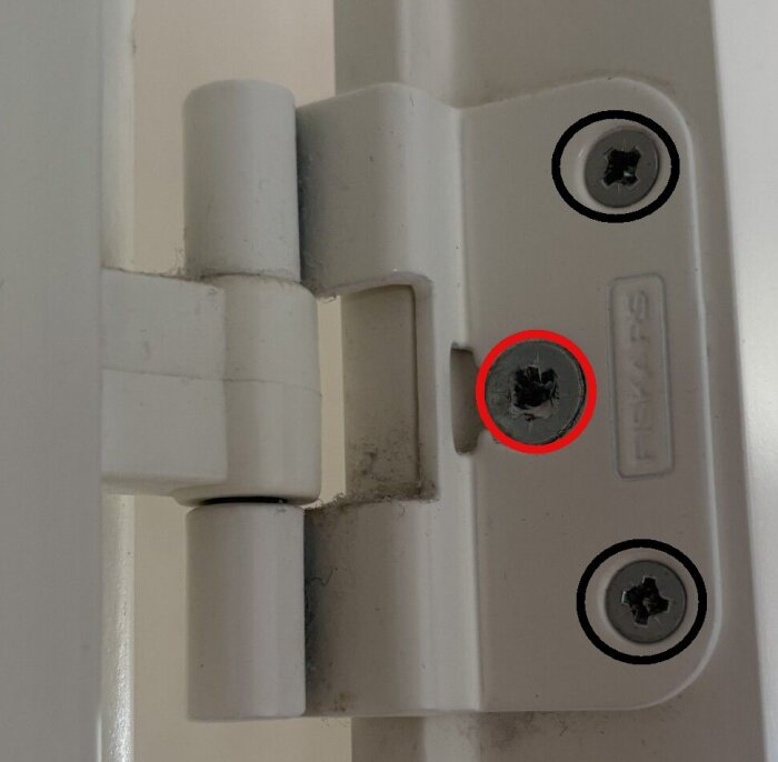 Dörrgångjärn med skruvar, två märkta med svart och en med rött. Visar instruktion för att lossa gångjärnets karmdel.