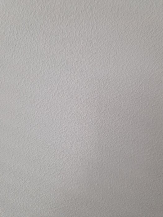 Knottrig väggyta efter första målningen i en lägenhet, visar ojämn struktur som kunden är missnöjd med efter spackling och slipning.