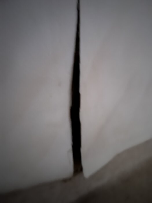 En spricka i en vägg eller golv, potentiellt kopplad till renoveringsbehov i ett badrum.