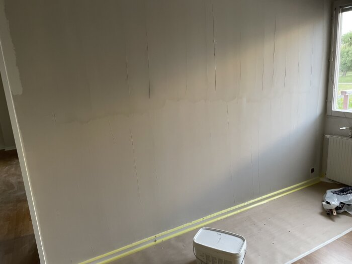 Väggar med oavslutat spackelarbete, inte spacklat helt upp till taket, med byggmaterial på golvet.