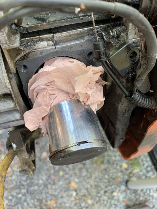 Motordel från röjsåg med ny cylinder installerad, omgiven av rosa tyg. Synliga vertikala märken på kolven.