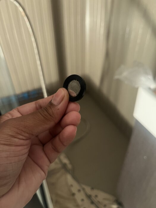 En hand håller ett litet nätfilter som ska placeras innan den silvriga kopplingen vid ett vattenläckageprojekt i ett bygg- och renoveringsforum.