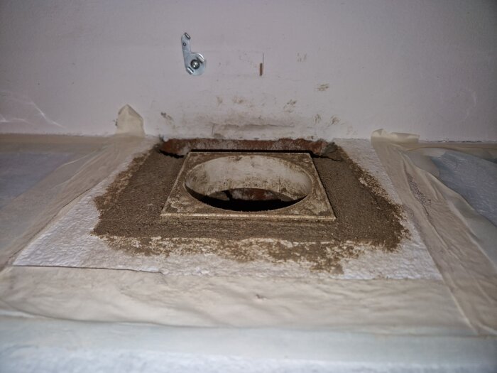 Ventilinstallation i vägg, täckt med bruk och tejp längs kanterna, förberedd för montering av innerdel inom bygg- och renoveringsprojekt.