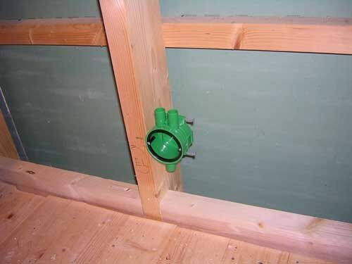 Grön dosa monterad i mitten av en träregelvägg under byggnation.