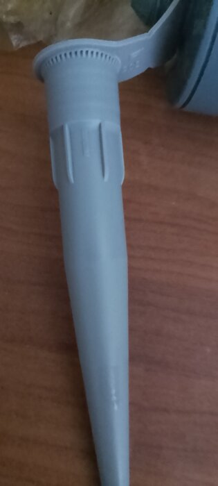 Grå silikonspets från Bostik, sedd på ett träbord.