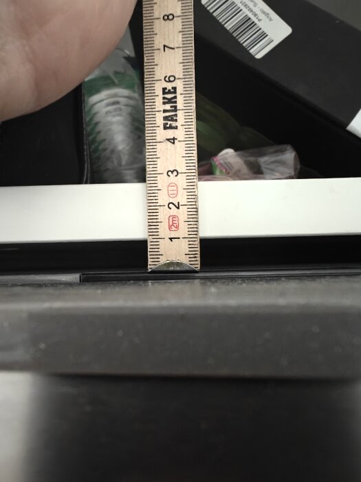 Linjal mäter avståndet mellan två köksskåp, visar ungefär 10 mm springa.