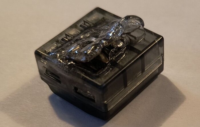 Bränd toppklämma med smält plast, troligen på grund av överbelastning vid laddning av elbil i ett garage.