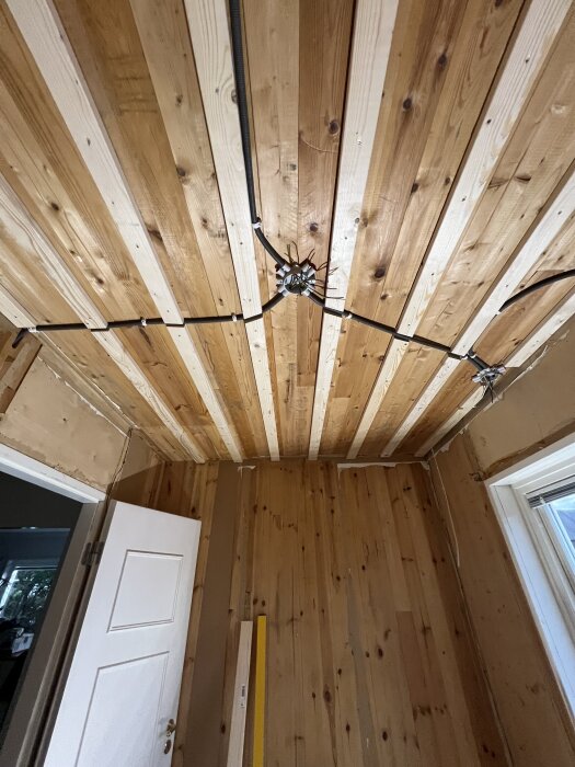 Tak med paneler och flexslang för eldragning i ett pågående projekt för att bygga ett barnrum, med pågående installation av takdosor.