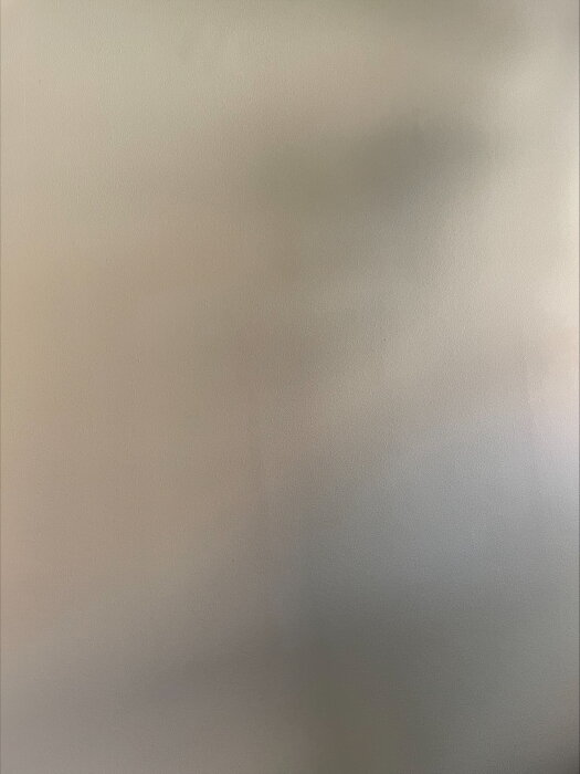 Vägg med synliga skuggor och oregelbundna mönster, troligen på grund av undermåligt underarbete med tapeter.