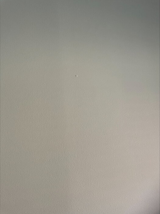 Närbild av en målad vägg med svaga vertikala linjer och luftbubblor synliga under ytan.