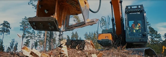 Grävmaskin med stubbefräs i arbete på kalhygge, stubbe blir flisad.