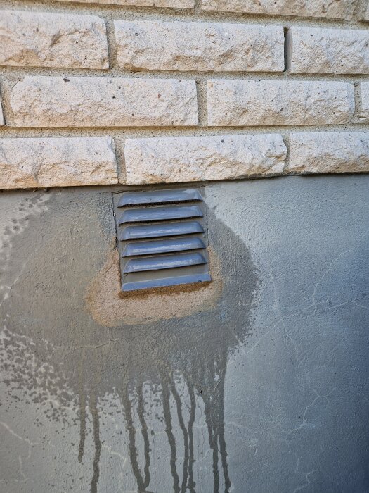 Ventilinstallation i tegelvägg med nylagt bruk runt ventilen. Synligt är fukt och märkbara spår av vatten på väggen.
