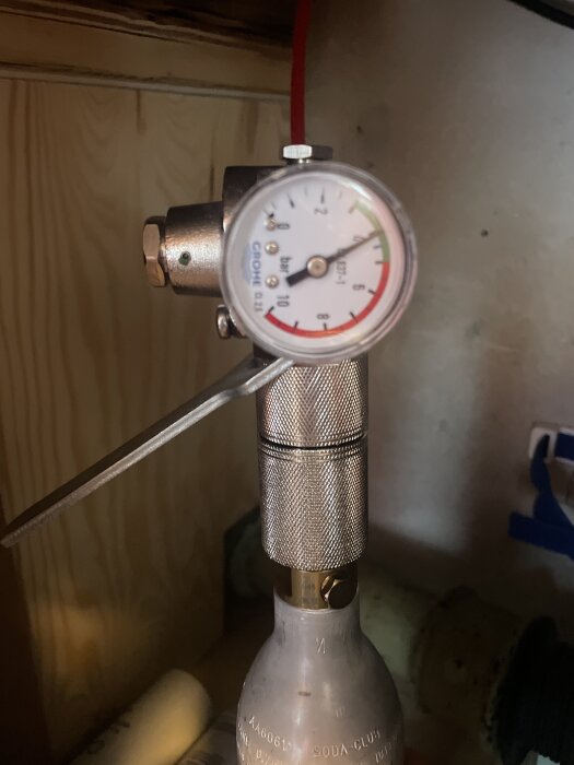 Tryckmätare och ventil på en Grohe Blue Professional kolsyrat system, monterat på en gaspatron i ett skåp.
