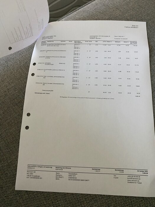 Foto av en faktura som ligger på en grå tygsoffa, texten visar olika byggmaterial och dess priser.