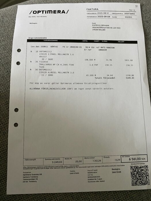 Faktura från Optimera Svenska AB för byggmaterial, inklusive träpanel och skruvar, med total belopp 6 561,00 SEK inklusive moms.