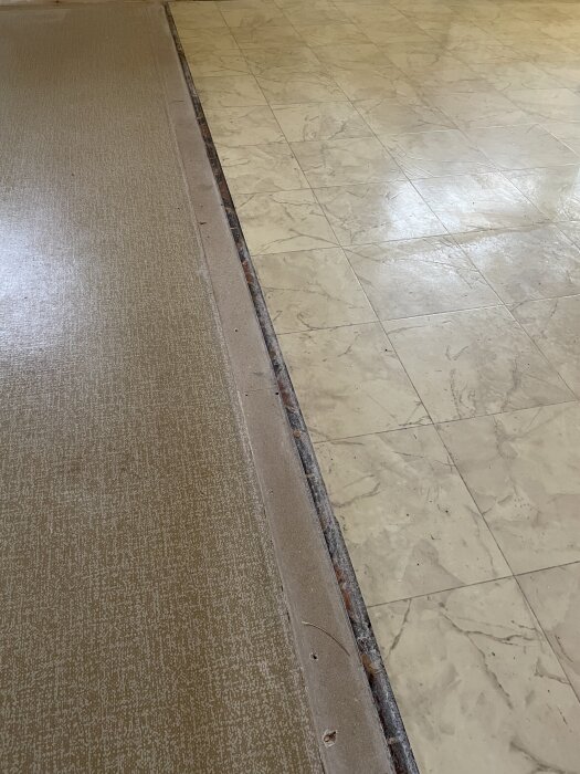 Gammalt vinylgolv i två olika färger med en synlig skarv efter att en vägg tagits bort.