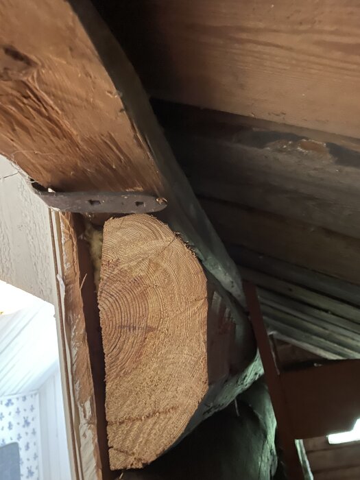 Träbjälke fastsatt med metallbeslag i taket.