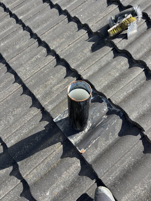 Rör på tegeltak utan lock, med borstar bredvid, på en villa från 70-talet.