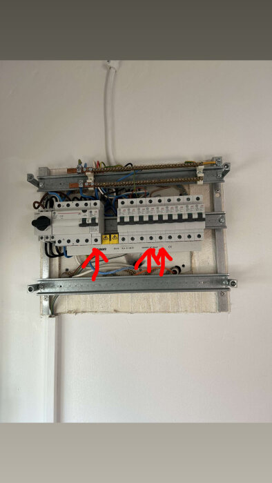 Elcentral med tre markerade huvudbrytare, från vänster säkrar av ugn, fläkt, diskmaskin och häll, framhävd med röda pilar.