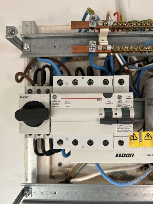 Bild på en elcentral med tre strömbrytare. Första till vänster säkrar ugn, mitten fläkt och diskmaskin, sista häll.