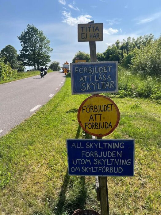 Skyltar vid väg som förbjuder att läsa skyltar, med texter som "Titta ej här" och "Förbjudet att läsa skyltar", omgivna av grönska.