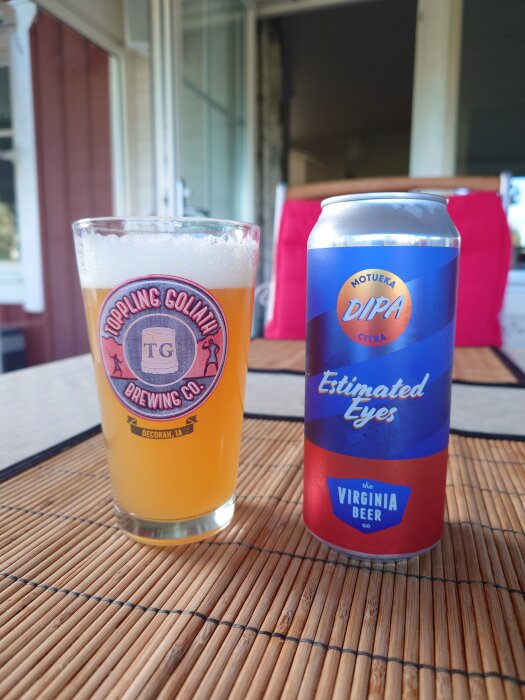 En ölburk märkt "Motueka DIPA" och ett glas med öl på ett bord med bambuduk.