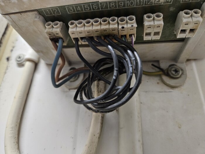 Kabelanslutningar med flera färgade kablar kopplade till en terminalblock i ett elskåp.